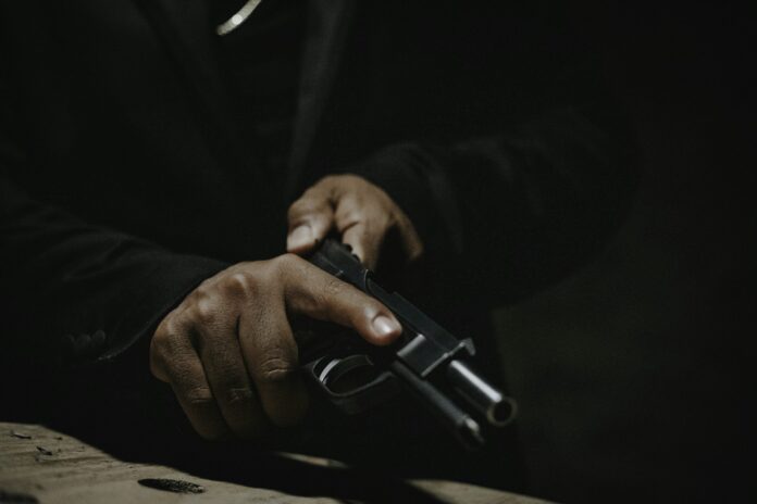 A man holding a handgun in low light representative image for the Sydney shooting incident where a gunman fired nearly 100 rounds, injuring 20 people before being arrested by police.